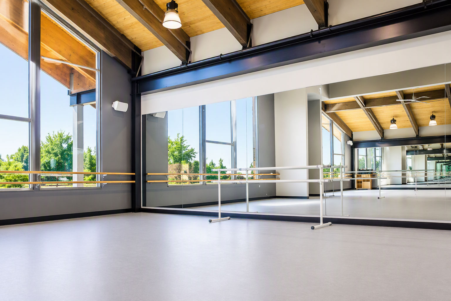 Modern dance studio featuring a Robbins L-Evate™ Heritage sprung dance floor with mirrored wall, ballet barres, and exposed timber beams