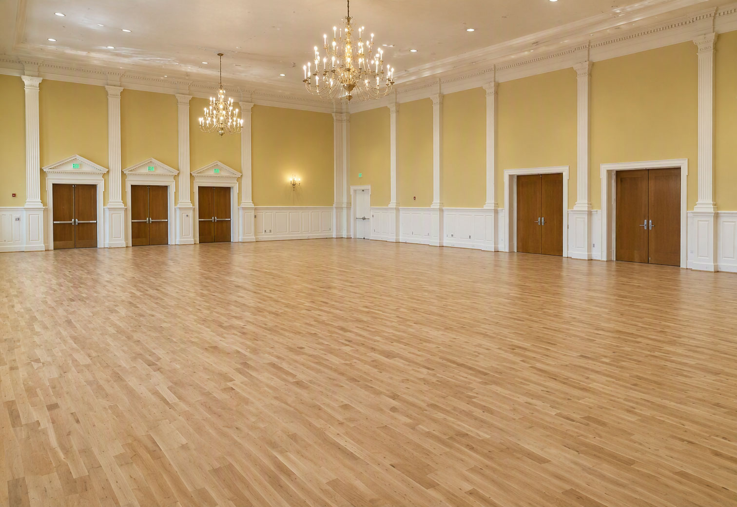 Elegant ballroom featuring Robbins hardwood maple dance flooring with a spacious open floor, chandeliers and classic architectural details